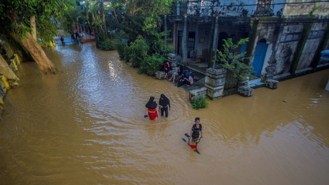 Warga berjalan melintasi banjir yang kembali merendam permukiman di Kecamatan Barabai, Kabupaten Hulu Sungai Tengah, Kalimantan Selatan, Jumat (19/11/2021). Foto: Bayu Pratama S/ANTARA FOTO