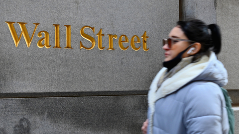 Seorang wanita berjalan melewati New York Stock Exchange (NYSE) di Wall Street. Foto: Angela Weiss / AFP