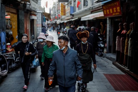Orang-orang berjalan di sebuah gang pasar di kota tua Lhasa, Tibet, China, Rabu (14/10/2020). Foto: THOMAS PETER/REUTERS