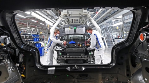 Max Bruehmann (kiri) dan Heiko Gruner (kanan) mengenakan masker aat mereka bekerja di lini produksi untuk model Volkswagen ID.3 listrik di Zwickau, Jerman. Foto: Hendrik Schmidt/dpa via AP