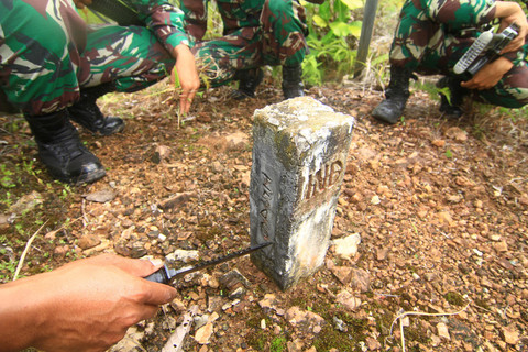 Anggota Satgas Pamtas RI-Malaysia Yonif 133/Yudha Sakti membersihkan tulisan nomor patok batas menggunakan pisau saat patroli di perbatasan Badau, Kabupaten Kapuas Hulu, Kalimantan Barat. Foto: Jessica Helena Wuysang/ANTARA FOTO