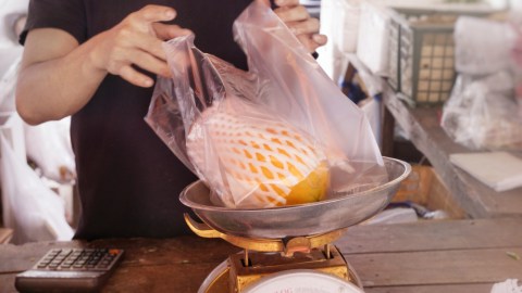 Ilustrasi pedagang membungkus buah dengan plastik Foto: Shutter Stock