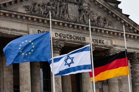 Bendera Israel, Jerman dan Uni Eropa terlihat di luar Parlemen Federal Jerman, Bundestag pada Hari Peringatan Holocaust Internasional, di depan gedung Reichstag, di Berlin, Jerman, 27 Januari 2022. Foto: REUTERS/Hannibal Hanschke