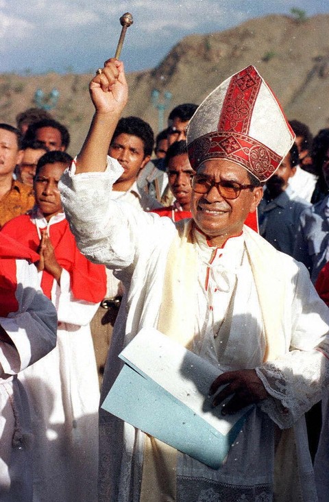 Peraih Nobel Perdamaian Uskup Carlos Filipe Ximenes Belo memercikkan air suci saat upacara pemberkatan patung Raja Kristus raksasa yang menghadap ke Teluk Dili (24/11/1996). Paus Fransiskus memberikan sanksi pada Belo atas kekerasan seksual. Foto: John Macdougall/ AFP