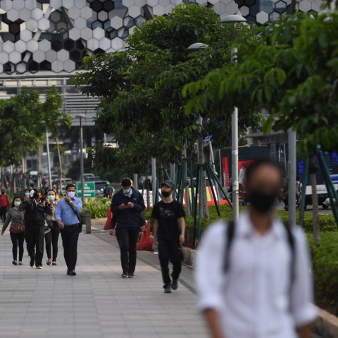 Sejumlah pekerja berjalan usai bekerja dengan latar belakang gedung perkantoran di Jl Jenderal Sudirman, Jakarta, Kamis (16/4) Foto: ANTARA FOTO/Akbar Nugroho Gumay