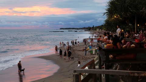 Wisatawan menikmati matahari terbenam di pantai Canggu di tengah pandemi penyakit virus corona (COVID-19) di Bali. Foto: REUTERS/Johannes P. Christo
