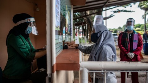 Petugas melayani wisatawan membeli tiket masuk saat berlangsungnya simulasi normal baru di TMII, Jakarta, Kamis (4/6). Foto: ANTARA FOTO/Aprillio Akbar