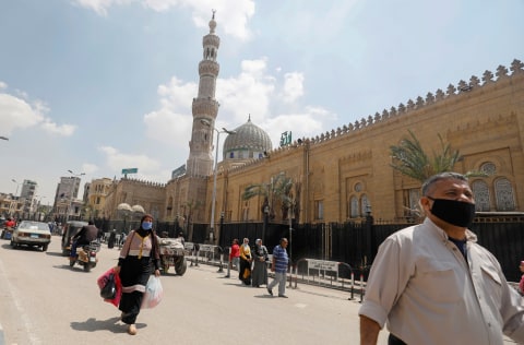 Warga memakai masker berjalan di depan Masjid El Sayeda Zainab yang ditutup di dekat pasar yang menjual lentera di Kairo, Mesir. Foto: REUTERS / Mohamed Abd El Ghany