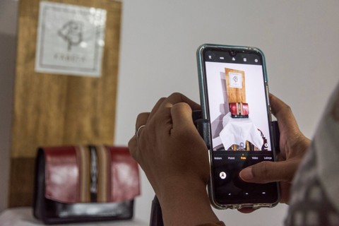 Proses pemotretan produk dompet tenun ikat Tanimbar dengan gawai untuk keperluan pemasaran digital di studio Kabeta Craft, Kota Ambon. Foto: FB Anggoro/ANTARA FOTO