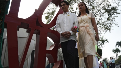 Sejumlah pasangan berdiri di sebelah patung huruf "LOVE" selama pernikahan massal di Manila, Filipina. Foto: AFP/TED ALJIBE