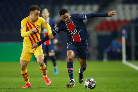 Pemain Paris Saint-Germain Layvin Kurzawa berebuat bola dengan pemain Barcelona Sergino Dest pada pertandingan leg kedua 16 besar Liga Champions di Parc des Princes, Paris, Prancis. Foto: Gonzalo Fuentes/REUTERS