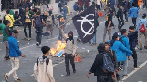 Seorang demonstran mengibarkan bendera Anarko saat demo di depan Gedung DPR, Selasa (24/9/2019). Foto: Helmi Afandi Abdullah/kumparan