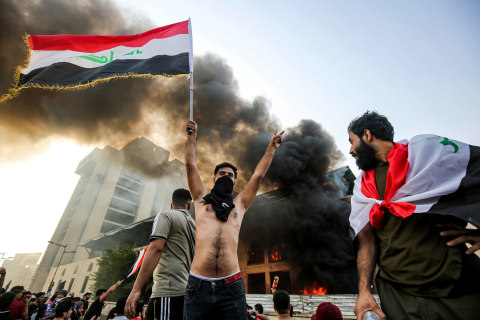 Seorang pemrotes bertopeng mengibarkan bendera nasional Irak selama demonstrasi menentang korupsi negara dan layanan yang buruk, antara ibukota Tahrir Square di Baghdad dan distrik Green Zone. Foto: AFP/AHMAD AL-RUBAYE