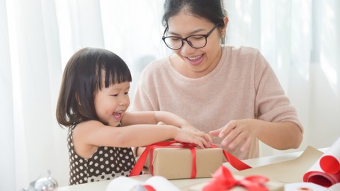 Anak membantu ibu membungkus kado. Foto: Shutter Stock