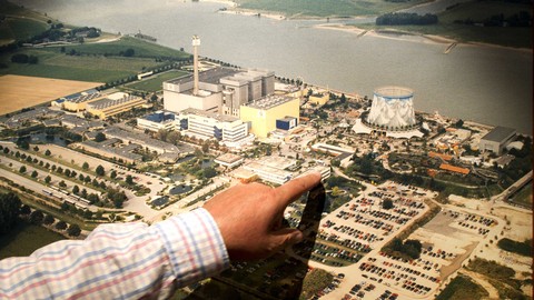 Seorang pria menunjuk pada foto yang menunjukkan pemandangan umum taman hiburan "Wunderland Kalkar" di bekas pembangkit listrik tenaga nuklir di Kalkar, Jerman barat. Foto: PATRIK STOLLARZ/AFP
