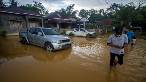 Warga berjalan melintasi banjir yang kembali merendam permukiman di Kecamatan Barabai, Kabupaten Hulu Sungai Tengah, Kalimantan Selatan, Jumat (19/11/2021). Foto: Bayu Pratama S/ANTARA FOTO