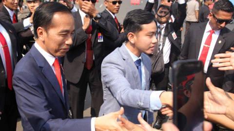 Presiden Joko Widodo (kiri) didampingi putranya Gibran Rakabuming (kanan) menyalami warga di depan Istana Negara, Jakarta, Minggu (20/10).  Foto: ANTARA FOTO/Rachman