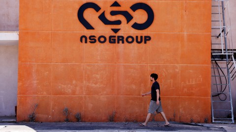 Seorang pria berjalan melewati logo perusahaan siber Israel NSO Group di salah satu cabangnya di Gurun Arava, Israel. Foto: Amir Cohen/REUTERS