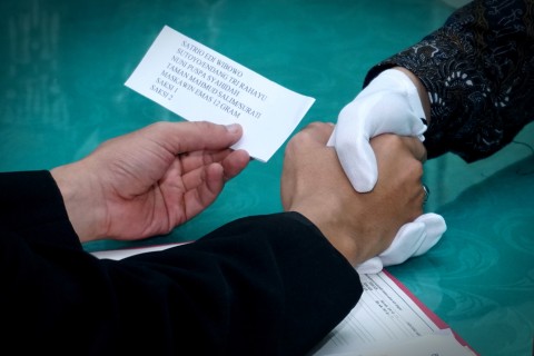 Satrio menggunakan sarung tangan saat melaksanakan prosesi akad nikah di Kantor KUA Bekasi Utara.  Foto: Iqbal Firdaus/kumparan