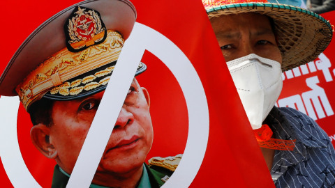 Seorang pengunjuk rasa memegang plakat dengan wajah Panglima Tertinggi, Jenderal Senior Min Aung Hlaing saat protes anti-kudeta di Mandalay, Myanmar, Senin (15/2). Foto: AP Photo