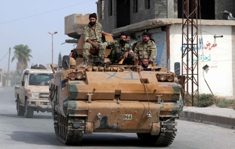 Pejuang pemberontak Suriah yang didukung Turki mengendarai truk militer di kota perbatasan Tel Abyad. Foto: Reuters