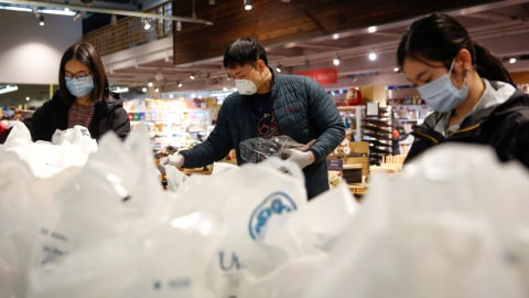 Anggota asosiasi memisahkan barang-barang belanjaan ke dalam tas dikirim ke manula secara gratis di Distrik Chinatown-International, di Seattle, AS. Foto: REUTERS/Lindsey Wasson