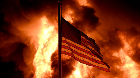 Api menyelimuti gedung Divisi Koreksi Komunitas saat bendera Amerika berkibar  Foto: Stephen Maturen/REUTERS