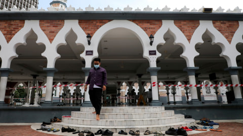 Seorang pria mengenakan masker saat berjalan menuruni tangga masjid, di Kuala Lumpur, Malaysia, Senin (16/3). Foto: REUTERS/Lim Huey Teng