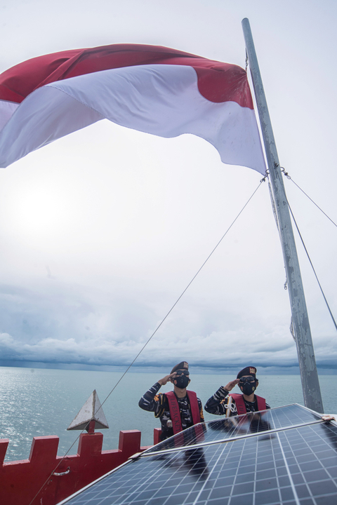 Taruna Akademi Angkatan Laut (AAL) mengibarkan bendera merah putih di atas Mercusuar Karang Unarang, Perairan Ambang Batas Laut (Ambalat), Nunukan, Kalimantan Utara. Foto: Muhammad Adimaja/Antara Foto