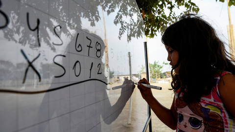 Siswa menulis di papan tulis di sekolah sementara yang didirikan di bawah pohon, di Guayaquil, Ekuador. Foto: Santiago Arcos/REUTERS