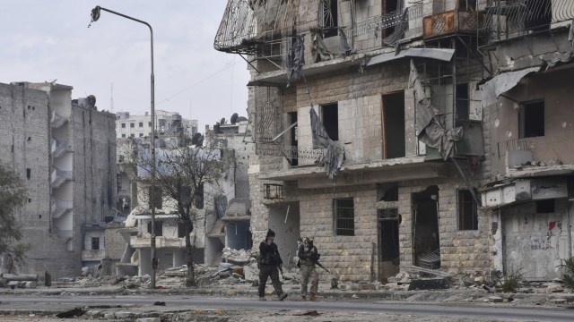 Dua tentara Suriah berjalan di wilayah Ansari, timur Kota Aleppo. (Foto: SANA via AP)