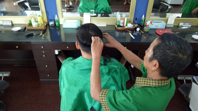 Abdul sedang mencukur rambut pelanggannya. (Foto: Kevin Kurnianto/kumparan)