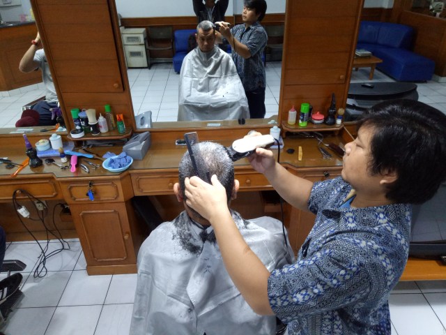 Luis ketika tengah mencukur rambut pelanggannya (Foto: Kevin Kurnianto)