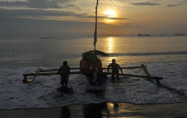 Perahu dan matahari terbit di pinggir laut. (Foto: Anis Efizudin/Antara)