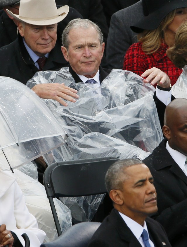 Repotnya George Bush mengenakan jas hujan. (Foto: Rick Wilking/Reuters)