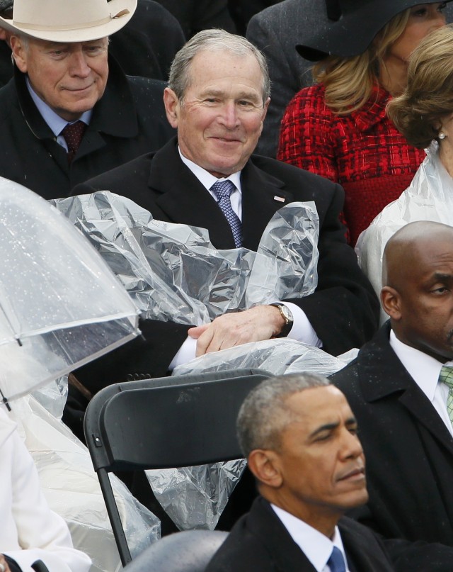 Senyum George Bush saat sibuk dengan jas hujan. (Foto: Rick Wilking/Reuters)