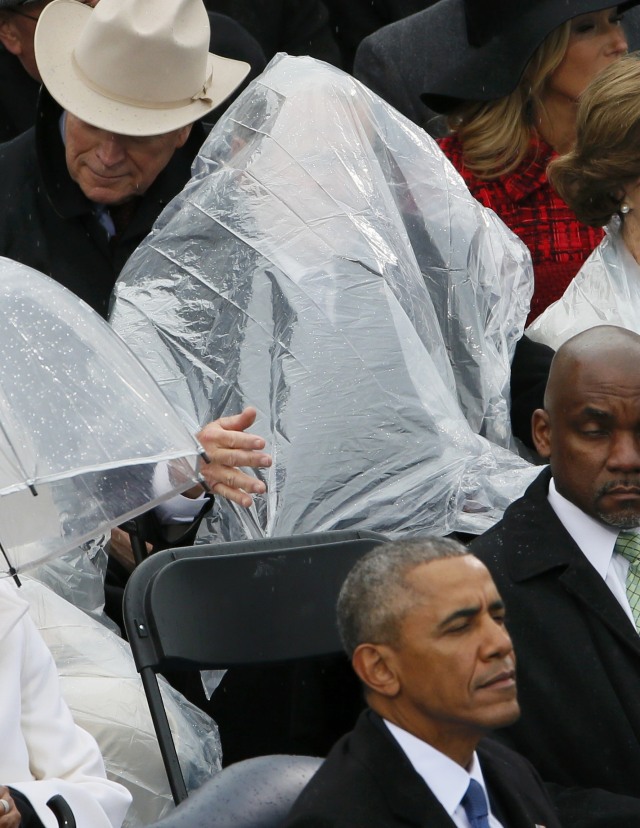 Wajah George Bush tertutupi oleh jas hujan. (Foto: Rick Wilking/Reuters)