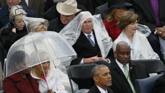 Bush sibuk pakai jas hujan saat Trump pidato. (Foto: Rick Wilking/Reuters)