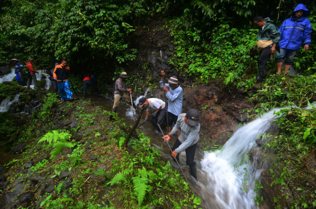 Membuka jalur irigasi sedikit demi sedikit (Foto: Adeng Bustomi/Antara)