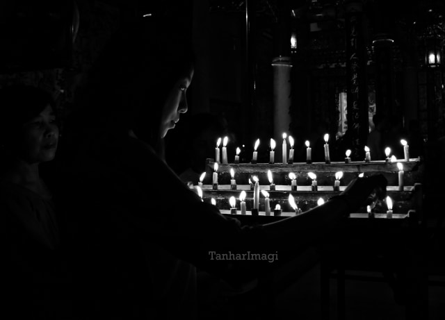 Seseorang tengah khusyuk menyalakan lilin (Foto: Kariadil H/TanharImagi)