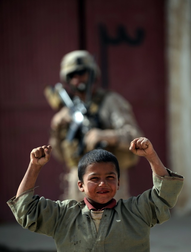 Seorang anak kecil dan tentara di belakangnya. (Foto: ADEK BERRY / AFP PHOTO)