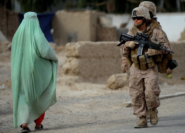 Seorang perempuan berpapasan dengan tentara (Foto: ADEK BERRY / AFP PHOTO)
