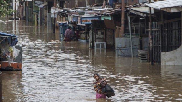 Warga melintasi banjir di Bukit Duri (Foto: Aprillio Akbar/Antara)