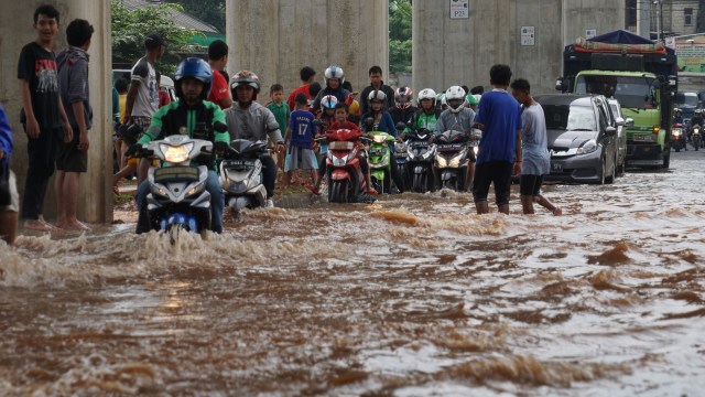 Pengedara sepeda motor melintasi jalan banjir. (Foto: Aditia Noviansyah/kumparan)