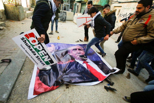 Seorang warga menginjak poster Trump. (Foto: REUTERS/Mussa Qawasma)