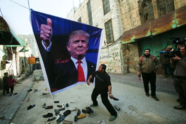 Warga yang ingin melempar sepatu ke poster Trump (Foto: REUTERS/Mussa Qawasma)