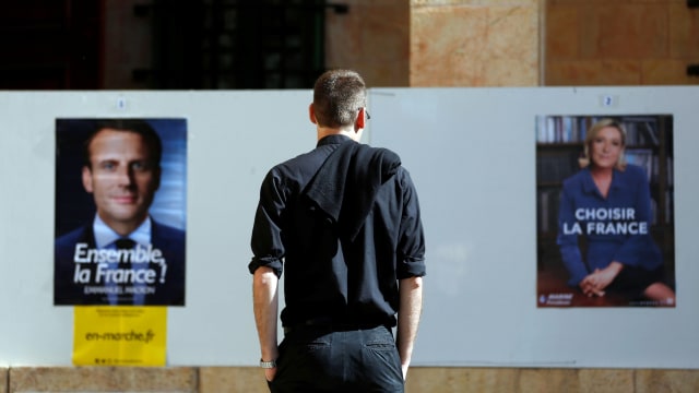 Warga Prancis di depan poster Macron dan Le Pen Foto: REUTERS/Ronen Zvulun