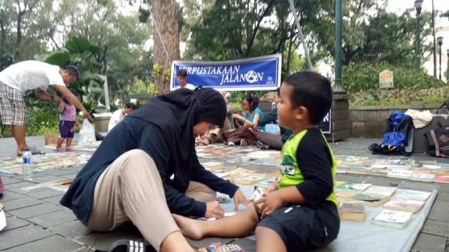 Ibu mengantarkan anaknya di perpustakaan jalanan. (Foto: Ardhana Pragota/kumparan)