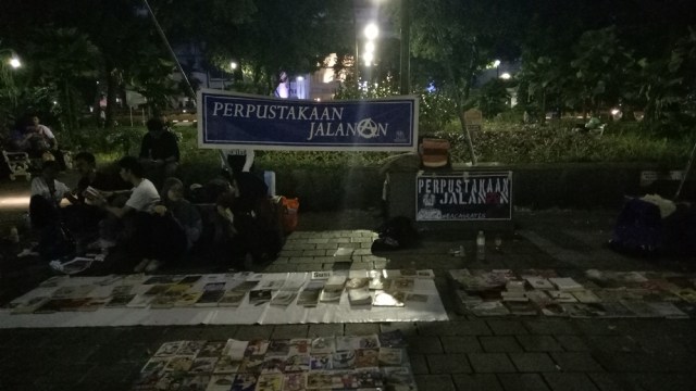 Suasana perpustakaan jalanan saat malam. (Foto: Ardhana Pragota/kumparan)