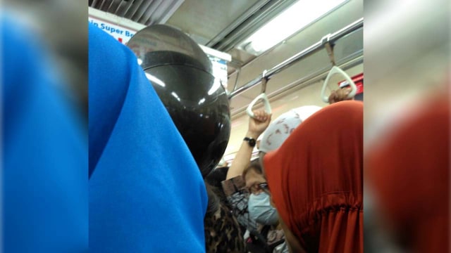 Ibu-ibu memakai helm di dalam kereta (Foto: Niken Anggun/kumparan)